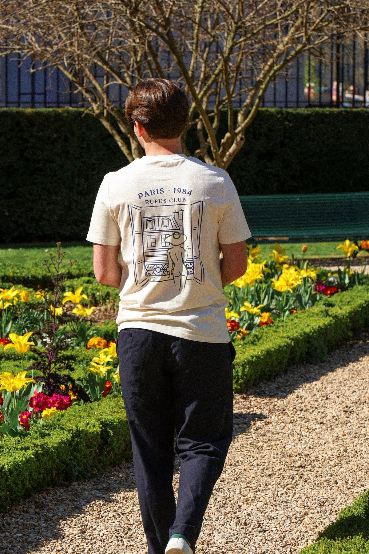 T-shirt La Parisienne Rufus Paris porté de dos dans un jardin parisien