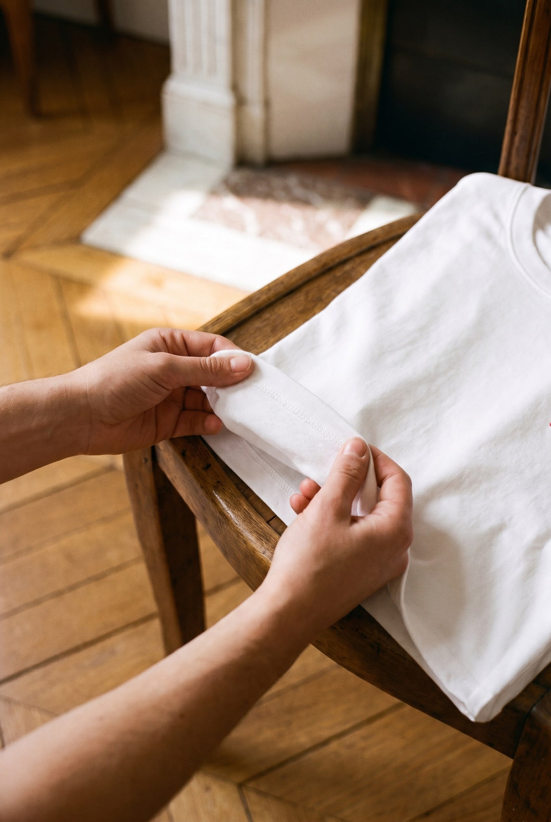 Mains qui soulèvent le t-shirt blanc brodé Amour posé sur une chaise
